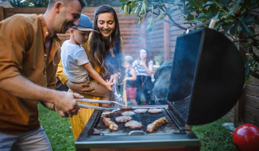 A family cooking barbeque in the backyard